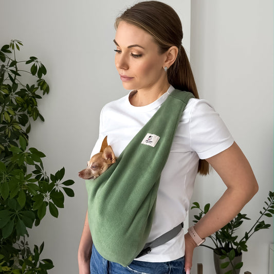 Woman carrying a small dog in an olive Fleece Security Dog Sling by Kokopaws