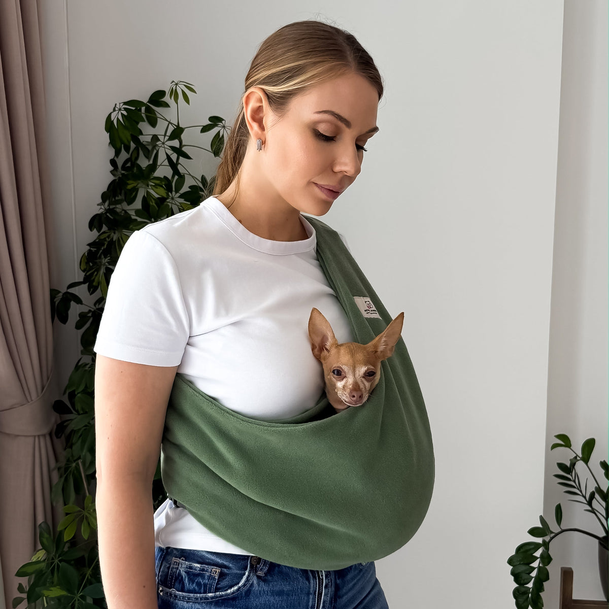 Woman carrying a small dog in an olive Fleece Security Dog Sling by Kokopaws
