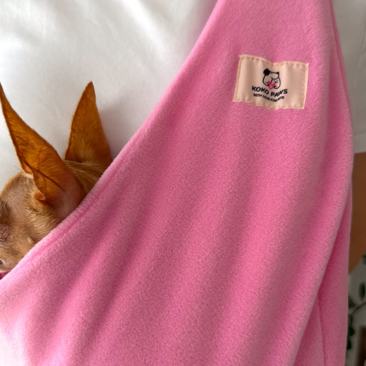 Small dog carried in a pink Fleece Security Dog Sling by Kokopaws
