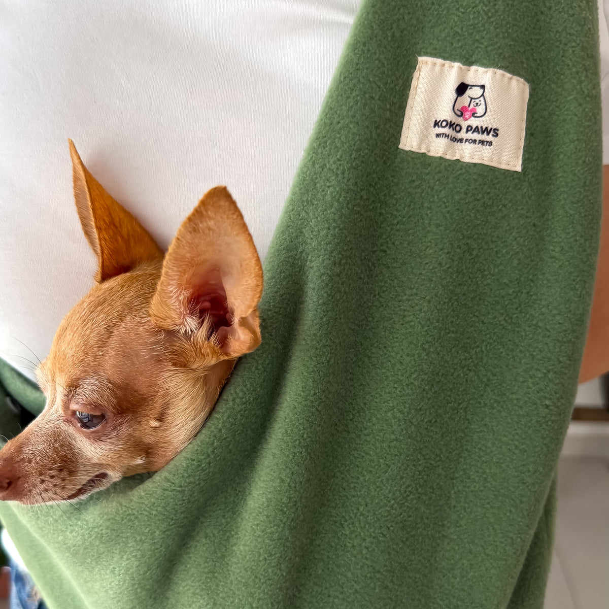 Woman carrying a small dog in an olive Fleece Security Dog Sling by Kokopaws