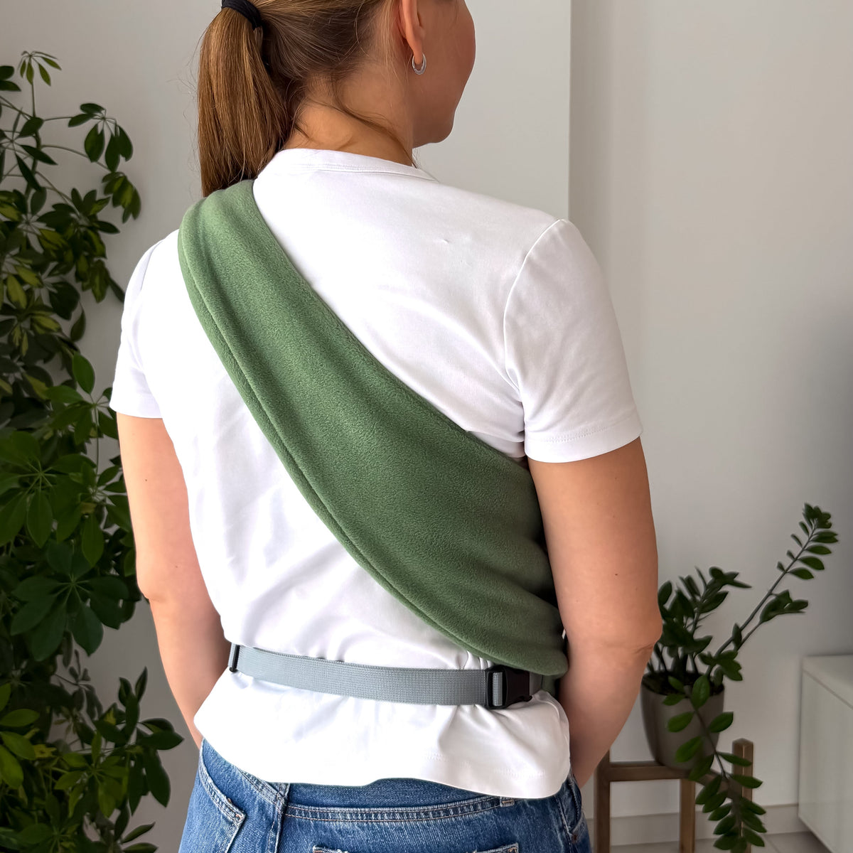 Woman carrying a small dog in an olive Fleece Security Dog Sling by Kokopaws