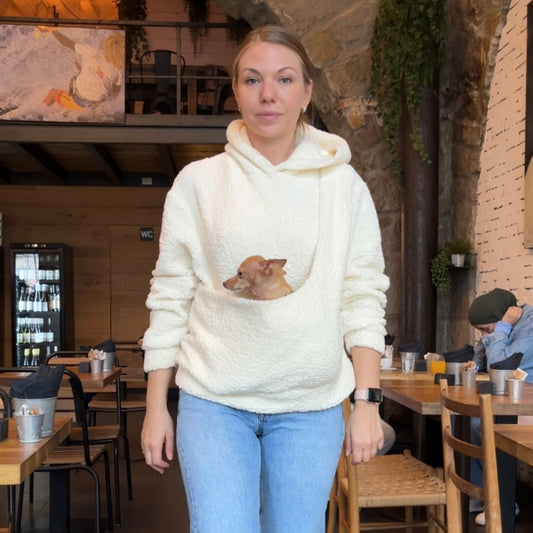 Woman in a white pet carrier kangoroo hoodie with a dog in the pocket