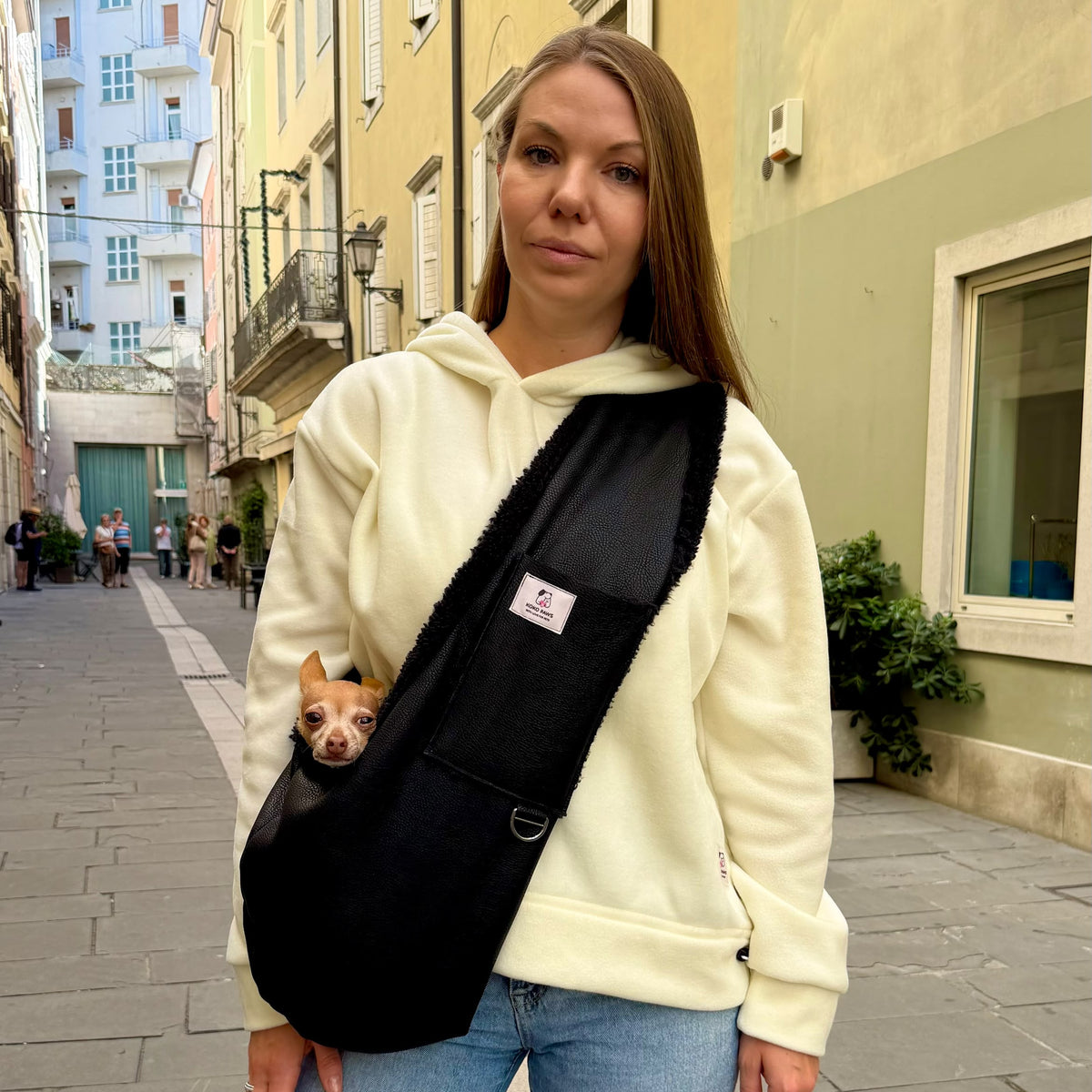 Hands-free black sling carrier for small dogs worn over the shoulder